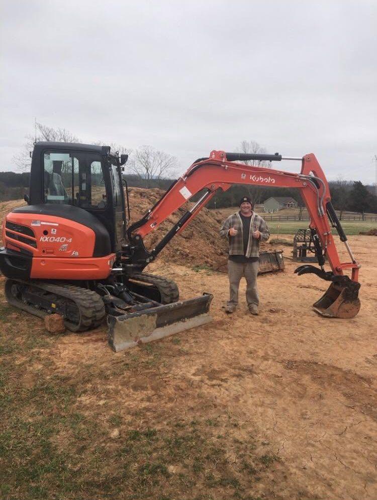 Giving a thumbs up next to a Yates mini excavator on a job site